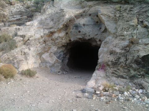1985 Toyota 4Runner - A dark mine entrance is visible in a rocky hillside, with sparse vegetation and some graffiti.