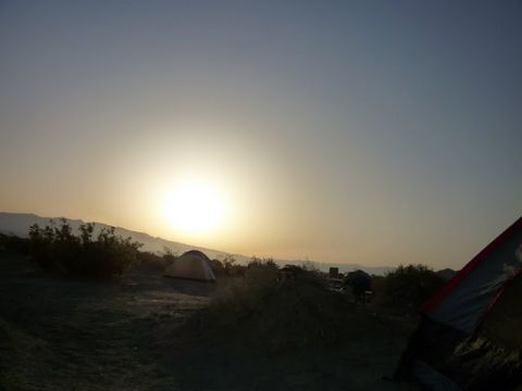 1985 Toyota 4Runner - Camping scene in the desert at sunset with tents pitched near mountains.