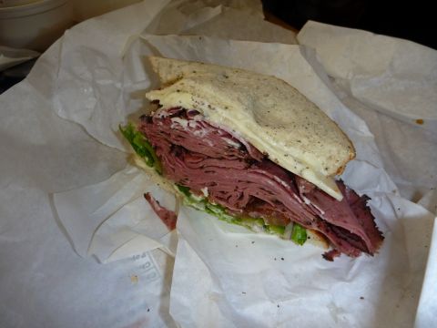 1985 Toyota 4Runner - A large sandwich with layers of meat and lettuce is wrapped in white paper.