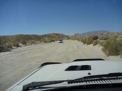 1985 Toyota 4Runner - Driving on a dirt road through a desert landscape with another vehicle ahead.