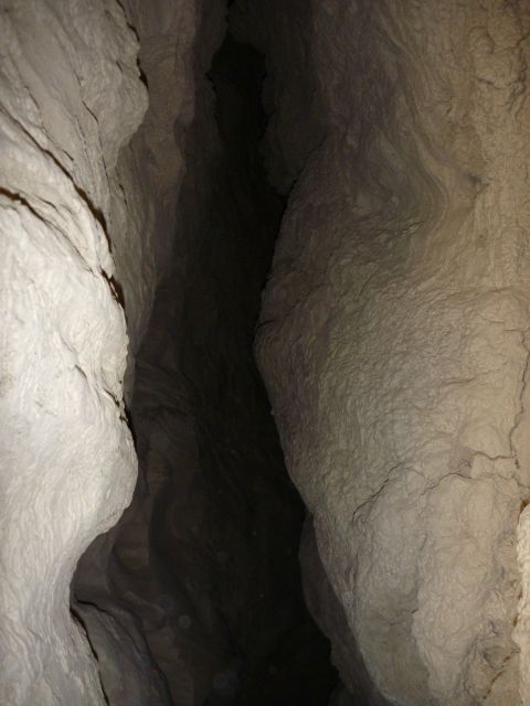 1985 Toyota 4Runner - The interior of a cave shows textured rock formations and a deep, dark passage ahead.