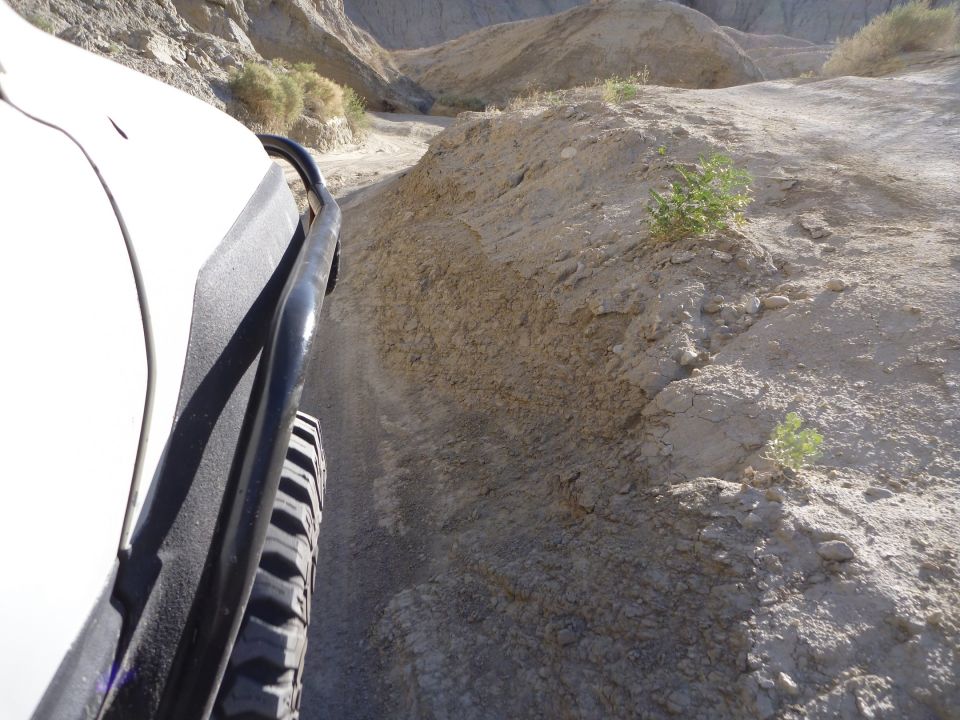 View from inside a vehicle driving on a dirt trail in a desert canyon