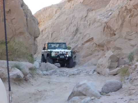 1985 Toyota 4Runner - Ford Bronco tackling a rough trail in a desert canyon.