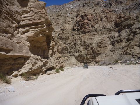 1985 Toyota 4Runner - An off-road vehicle navigates a dusty canyon road under a clear blue sky.