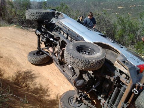 1985 Toyota 4Runner - SUV rolled over on a dirt trail, showing its undercarriage and suspension components.