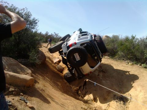 1985 Toyota 4Runner - A white SUV is overturned on a steep, rocky incline during an off-road excursion.