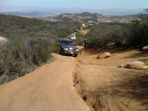 1985 Toyota 4Runner - Multiple SUVs navigate a challenging off-road trail with a scenic vista in the background.