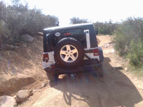 1985 Toyota 4Runner - Jeep Wrangler navigating a challenging off-road trail with rocky terrain.