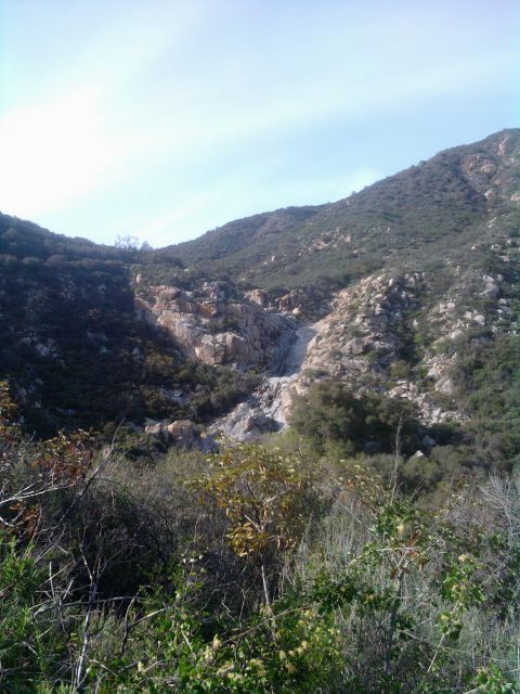1985 Toyota 4Runner - A dry creek bed winds through a rocky mountain landscape with scrub brush and trees.