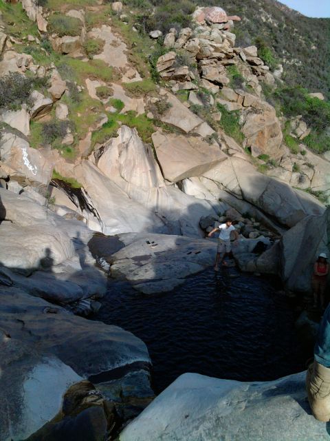 1985 Toyota 4Runner - People explore a rocky area with a pool of water, near a mountain slope.