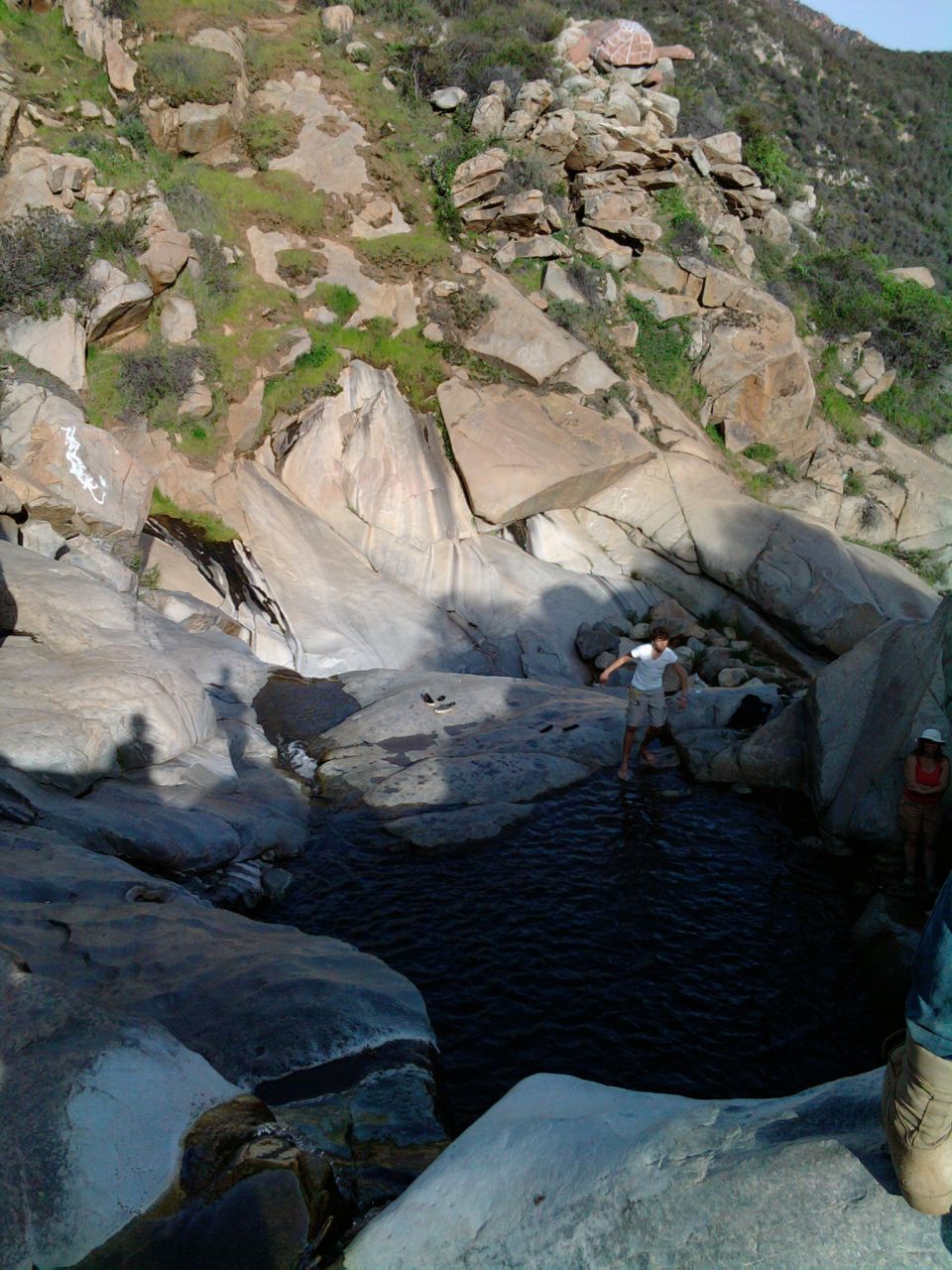 Rocky terrain with a small pool of water and people. A watermark reads 'SUPERMOTORS'