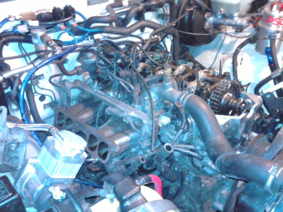 Engine bay with exposed engine components, hoses, and wiring. Visible text: SUPERMOTORS
