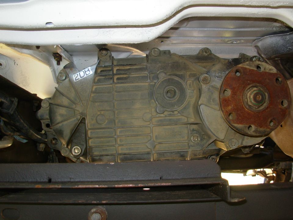 Underside view of transfer case with rusty output flange and '2DB' marking