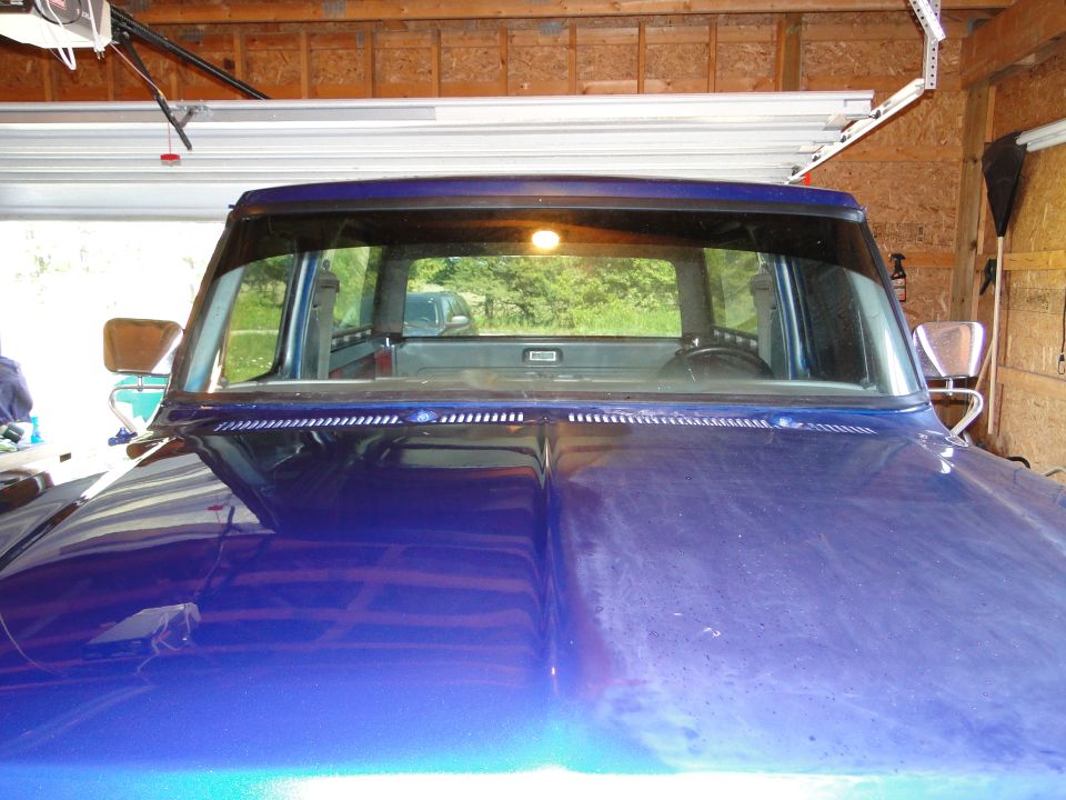 1978 Ford Bronco interior showing dashboard and rear window view; blue hood in foreground