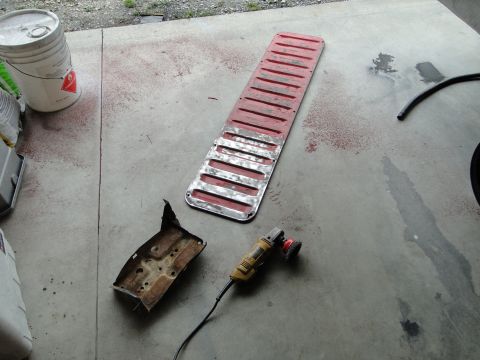1978 Ford Bronco - Car parts and a grinder are laid out on a concrete surface, possibly for restoration.