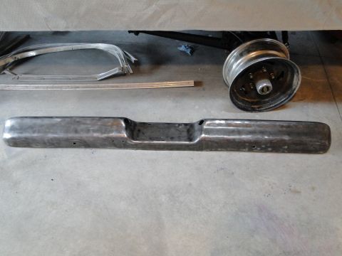 1978 Ford Bronco - A chrome bumper and a chrome wheel are displayed on a concrete floor, possibly for restoration or sale.
