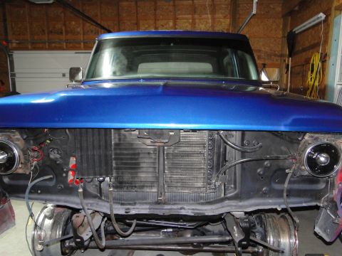 1978 Ford Bronco - The front end of a blue pickup truck is disassembled, revealing the radiator and engine components.