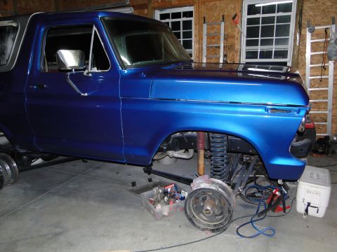 1978 Ford Bronco - A blue 1978 Ford Bronco is shown in a garage with its front wheel off, indicating repair work.
