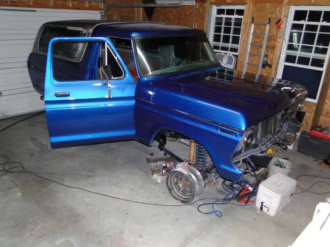 1978 Ford Bronco - This blue Ford Bronco is undergoing repairs in a garage, with its front end partially dismantled.