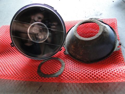 1978 Ford Bronco - Headlight assembly and its associated housing are displayed on a red mesh mat. The word 'TOP' is visible on the headlight lens.