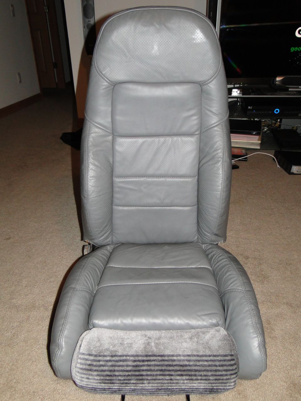 Gray leather car seat with perforated headrest and striped fabric base