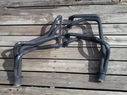 1993 Ford Bronco - A pair of black exhaust headers are displayed on weathered wooden planks, with a SuperMotors watermark visible.
