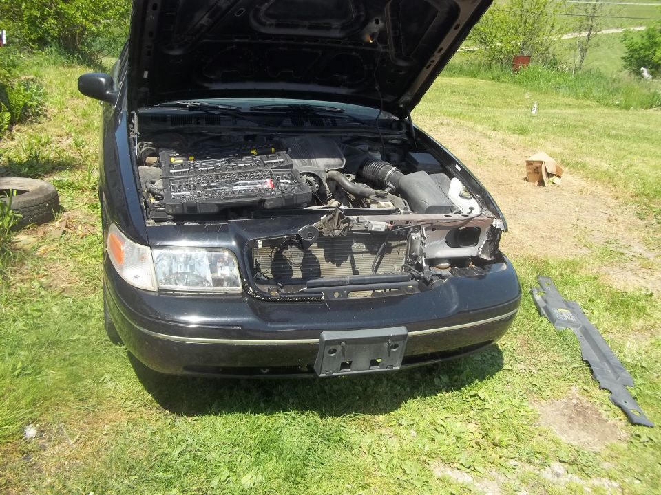 Front view of a black 2004 Ford Crown Victoria with the hood open, showing the engine and a toolbox