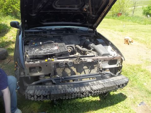 2004 Ford Crown Victoria - The front end of a car is disassembled, revealing the engine and various components under the open hood.