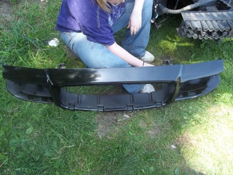2004 Ford Crown Victoria - A person is holding a black car bumper on the grass.