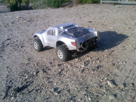 1986 Ford Bronco - This remote control monster truck is captured in a three-quarter front view on a gravelly surface.