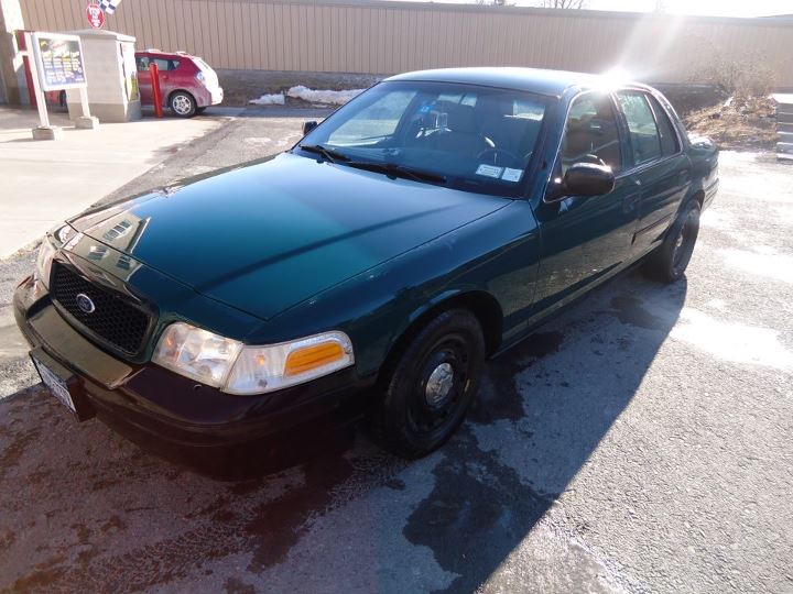 Dark green 2003 Ford Crown Victoria parked on asphalt, with a red SUV in the background