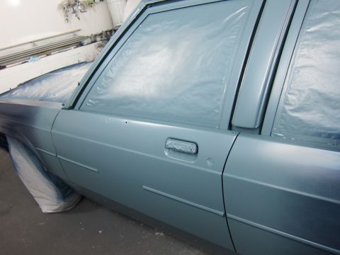1991 Ford LTD Crown Victoria - A car's side door and window are covered in plastic sheeting, likely during a painting process.