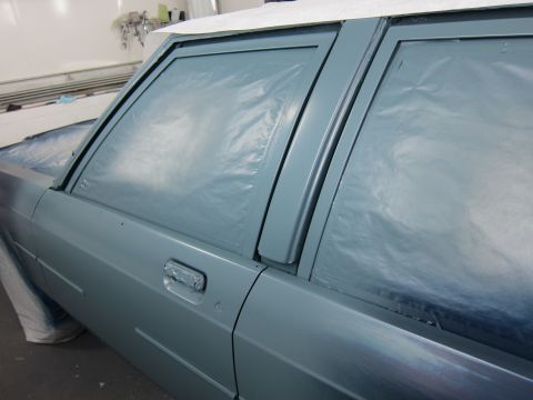 1991 Ford LTD Crown Victoria - A car's side door and windows are covered in plastic sheeting, suggesting it is being prepped for painting.