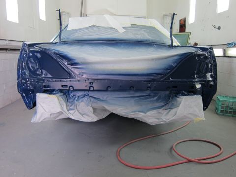 1991 Ford LTD Crown Victoria - A car is being prepped for painting inside a booth, with plastic sheeting covering most of the body.