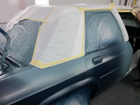 1991 Ford LTD Crown Victoria - A car's side is masked off and ready for a new coat of paint in a workshop.