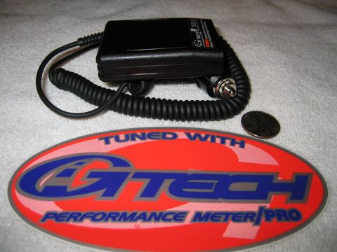 2002 Ford Taurus - Black G-Tech performance meter accelerometer unit with a coiled power cord and lighter-socket plug, laid on a white towel next to a coin fo…