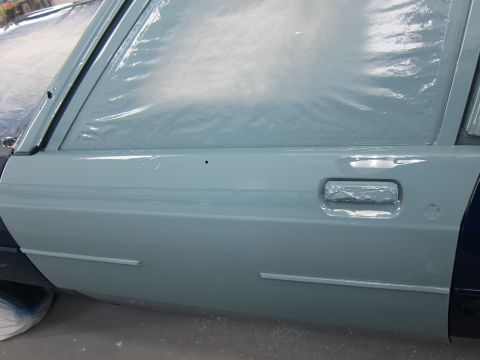 1991 Ford LTD Crown Victoria - A car door is covered in plastic sheeting and appears to be undergoing a paint job, with the door handle taped for protection.