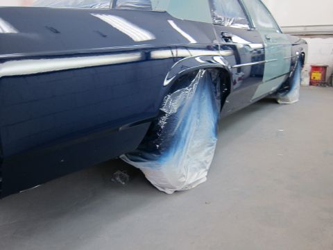 1991 Ford LTD Crown Victoria - A car's rear quarter panel and door are covered in plastic sheeting, indicating it is undergoing a painting process.