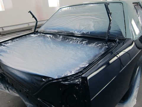 1991 Ford LTD Crown Victoria - A car's rear is covered in plastic sheeting, likely for a paint job.