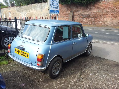 1980 MINI Cooper - A blue 1980 MINI Cooper is parked outside a business with a 'For Sale' sign in the window.