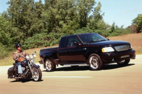 2007 Ford Mustang - A black Ford F-150 Lightning pickup truck is seen on the road alongside a motorcycle.