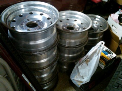 1986 Ford Bronco - Several aluminum wheels are stacked together, with a plastic bag and a box nearby.