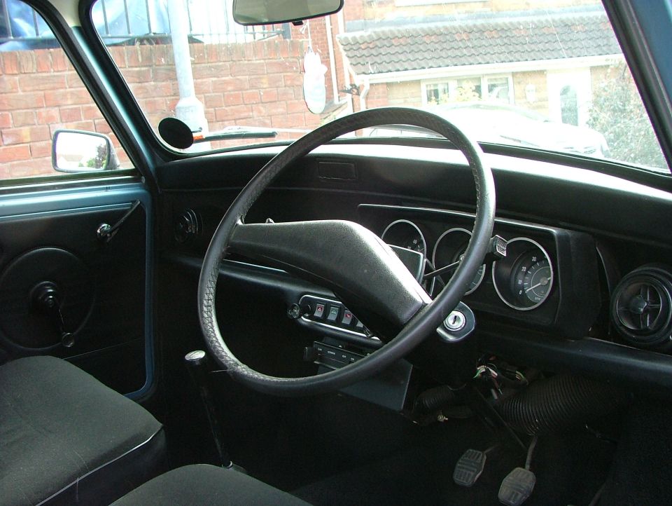 Right-hand-drive classic Mini dashboard with center gauges and thin steering wheel