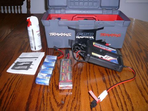 1988 Ford Bronco - Traxxas F-150 Raptor RC car charger, batteries, and toolbox with tools.