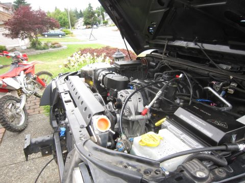 2008 Jeep Wrangler - The engine bay of a Jeep is open, revealing its components and a dirt bike parked to the side.