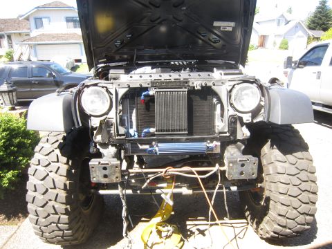 2008 Jeep Wrangler - This Jeep Wrangler's front end is exposed with the hood up, revealing its engine bay and aftermarket cooling systems.