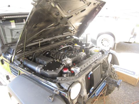 2008 Jeep Wrangler - The engine bay of a Jeep Wrangler is shown with the hood open, revealing aftermarket modifications to the engine and cooling system.
