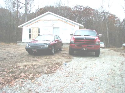 1997 Ford Taurus - Two vehicles are parked outside a house that is undergoing construction.
