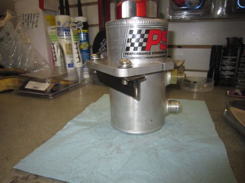2008 Jeep Wrangler - Aluminum power steering reservoir with PSC logo and red cap, mounted on a workbench.