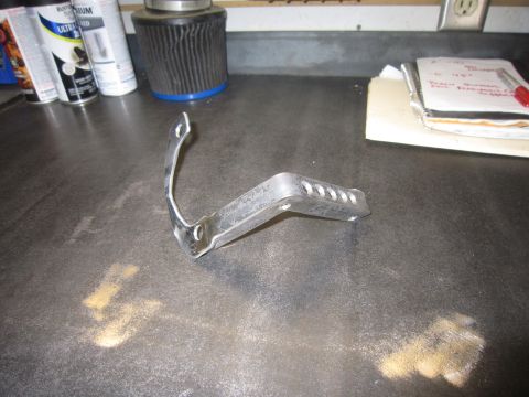 2008 Jeep Wrangler - Metal bracket with holes on a workbench next to spray cans and a notebook.